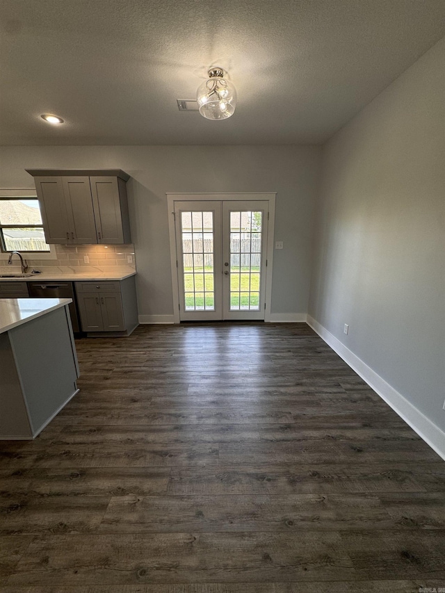 unfurnished dining area with sink, a textured ceiling, french doors, and dark hardwood / wood-style floors