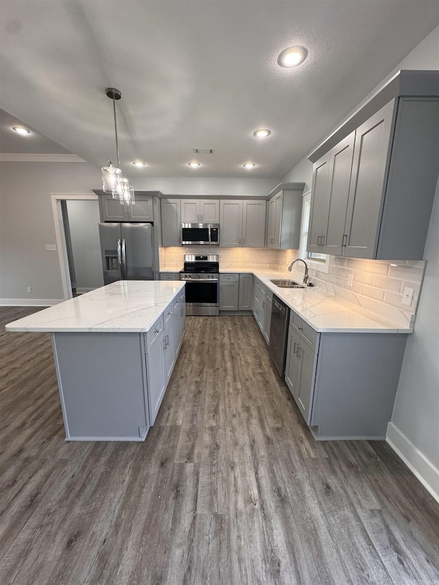 kitchen featuring sink, hanging light fixtures, a kitchen island, gray cabinetry, and appliances with stainless steel finishes