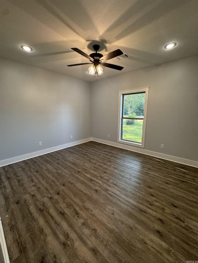 spare room featuring ceiling fan, dark wood-type flooring, and a textured ceiling