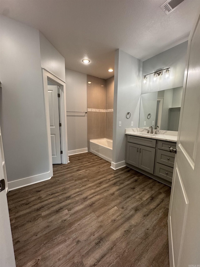 bathroom with a textured ceiling, shower / bathing tub combination, vanity, and wood-type flooring