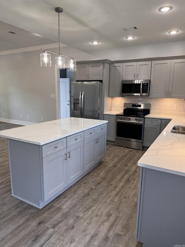 kitchen featuring stainless steel appliances, light stone countertops, hanging light fixtures, and gray cabinets