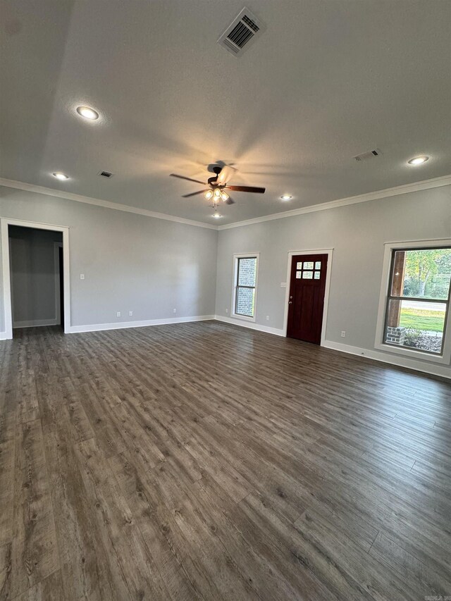 unfurnished living room with ornamental molding, dark wood-type flooring, a wealth of natural light, and ceiling fan