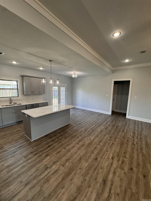 kitchen featuring gray cabinetry, pendant lighting, dark wood-type flooring, a kitchen island, and sink