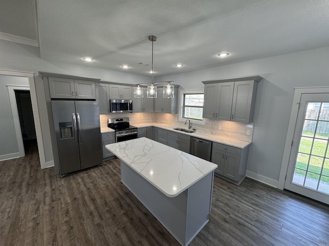 kitchen featuring a kitchen island, appliances with stainless steel finishes, decorative backsplash, and sink