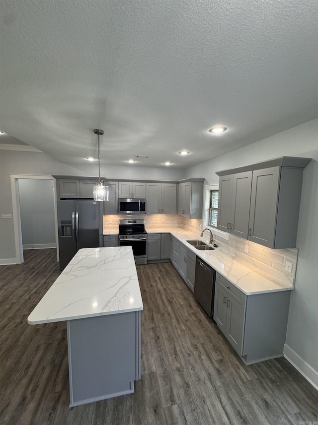 kitchen featuring a center island, decorative light fixtures, gray cabinets, appliances with stainless steel finishes, and sink