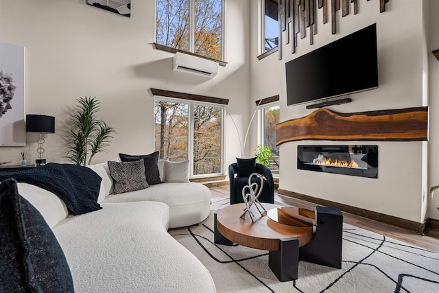 living room with a high ceiling, light hardwood / wood-style flooring, and an AC wall unit