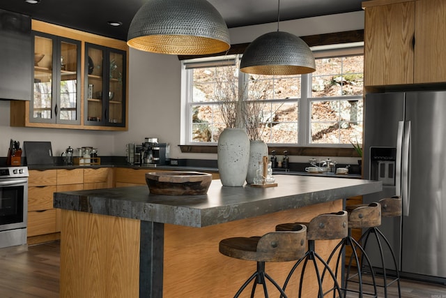 kitchen featuring appliances with stainless steel finishes, dark wood-type flooring, a breakfast bar area, and pendant lighting