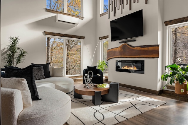 living room with wood-type flooring, a high ceiling, and a wall mounted AC