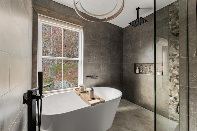 bathroom with tile walls, plenty of natural light, and shower with separate bathtub