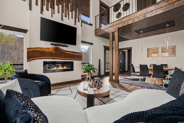 living room with a high ceiling, a healthy amount of sunlight, and light hardwood / wood-style floors