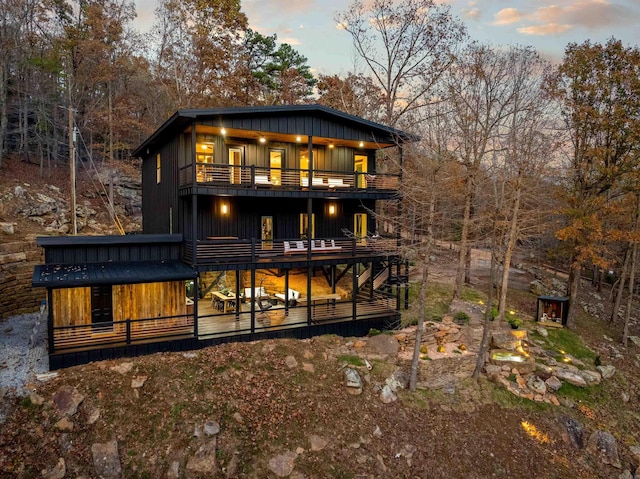 back house at dusk with a deck and a balcony