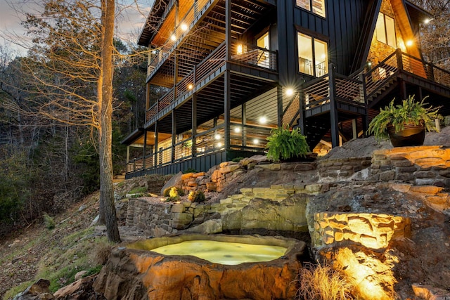 property exterior at dusk featuring a balcony and an outdoor hot tub