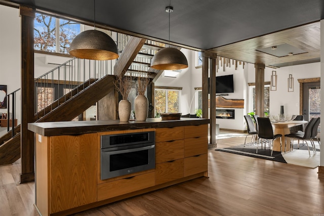 kitchen with oven, light wood-type flooring, an AC wall unit, and hanging light fixtures