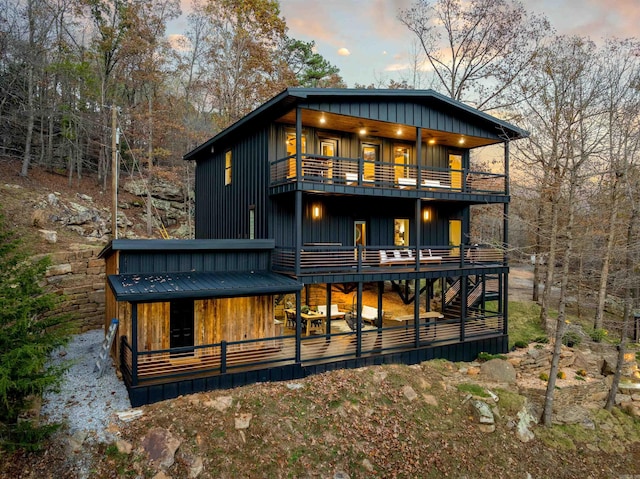 back house at dusk with a balcony and a wooden deck