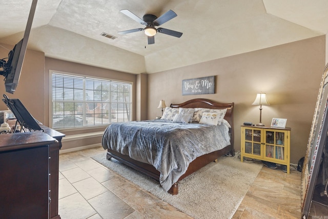 bedroom with ceiling fan, vaulted ceiling, and a tray ceiling