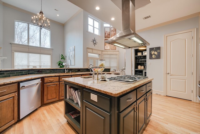 kitchen featuring a notable chandelier, a center island with sink, light stone countertops, appliances with stainless steel finishes, and island range hood