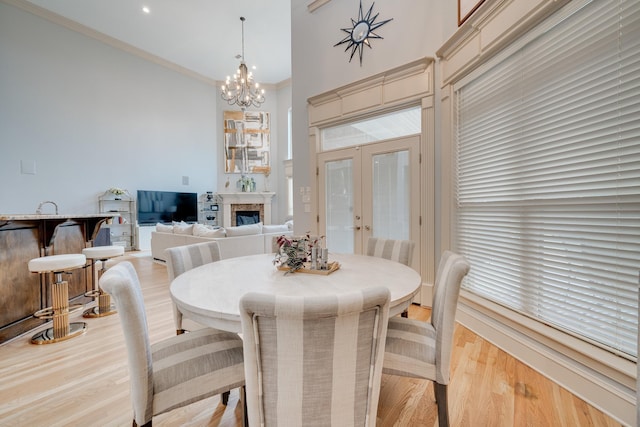 dining room with light wood-type flooring, a notable chandelier, french doors, and crown molding