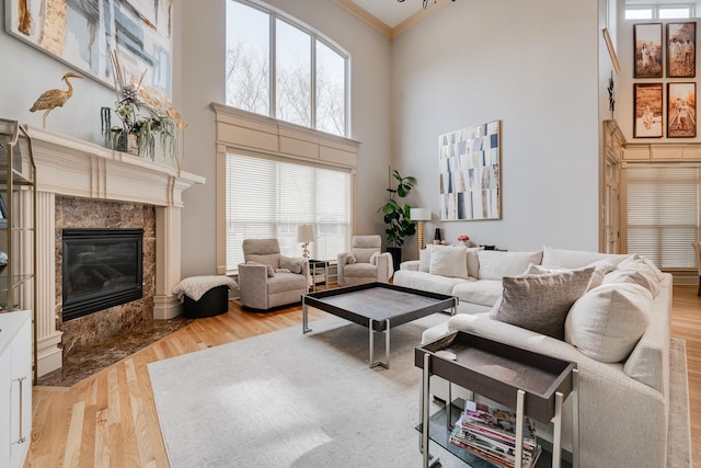 living room with a high end fireplace, ornamental molding, a towering ceiling, and wood-type flooring