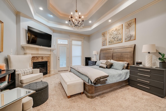 bedroom featuring light colored carpet, a tile fireplace, a raised ceiling, an inviting chandelier, and ornamental molding