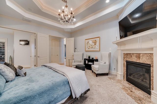 bedroom featuring an inviting chandelier, a fireplace, a tray ceiling, and ornamental molding