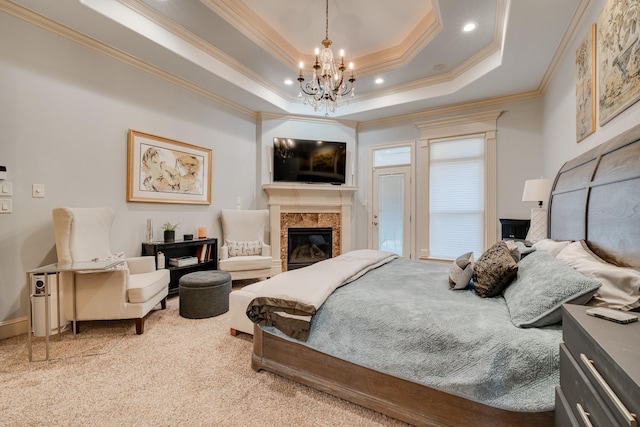 bedroom featuring carpet, a premium fireplace, crown molding, a tray ceiling, and a chandelier