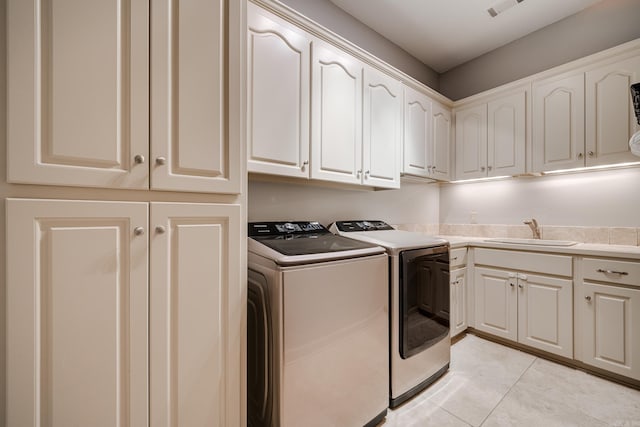 laundry area featuring light tile patterned floors, washing machine and dryer, sink, and cabinets