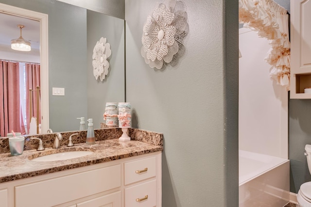 bathroom with toilet, a tub to relax in, and vanity