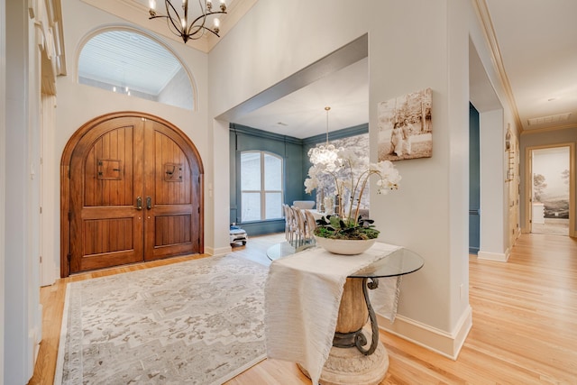 foyer entrance with light hardwood / wood-style floors, crown molding, and an inviting chandelier