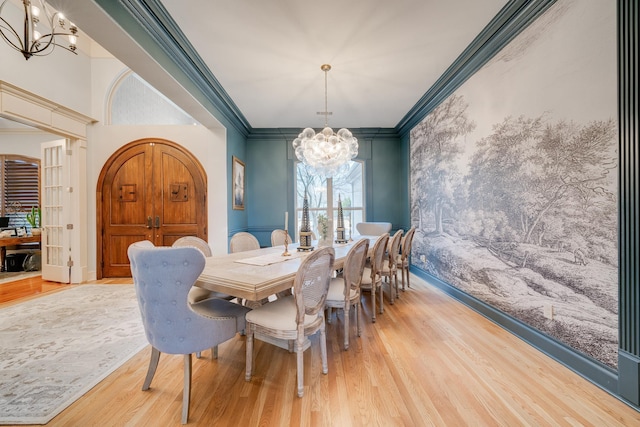 dining room with light wood-type flooring, ornamental molding, and a chandelier