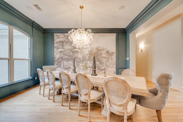 dining room with ornamental molding, light hardwood / wood-style flooring, and a notable chandelier