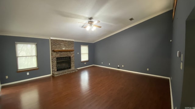 unfurnished living room featuring a brick fireplace, ceiling fan, ornamental molding, and a wealth of natural light