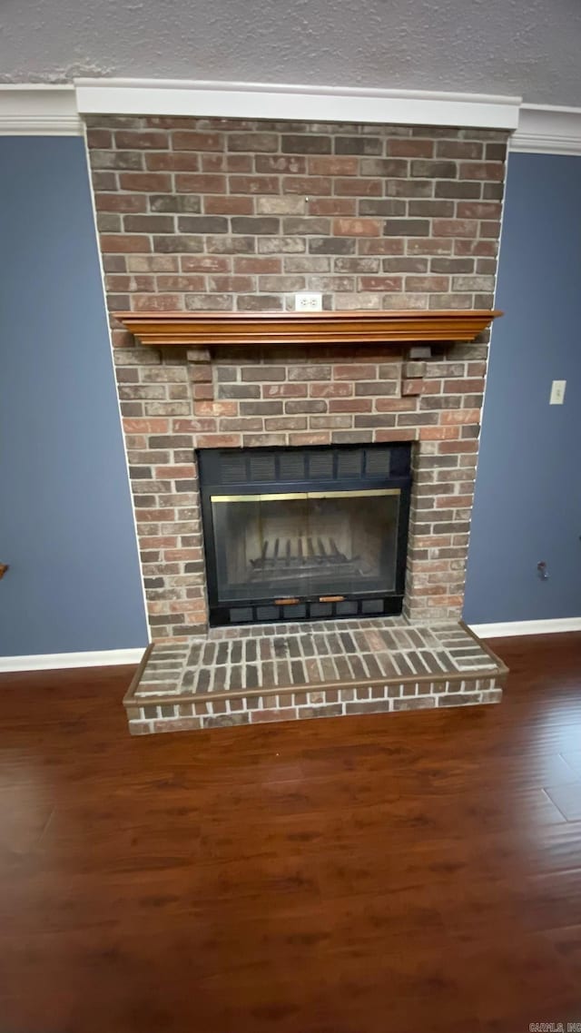 interior details featuring a brick fireplace, hardwood / wood-style flooring, and crown molding