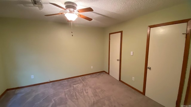 unfurnished bedroom featuring ceiling fan, light carpet, and a textured ceiling