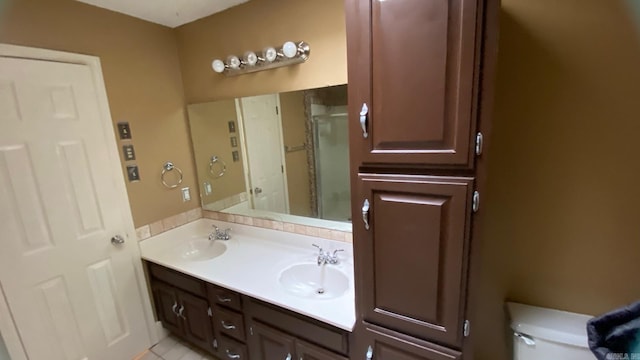 bathroom featuring toilet, tile patterned flooring, vanity, and a shower with shower door