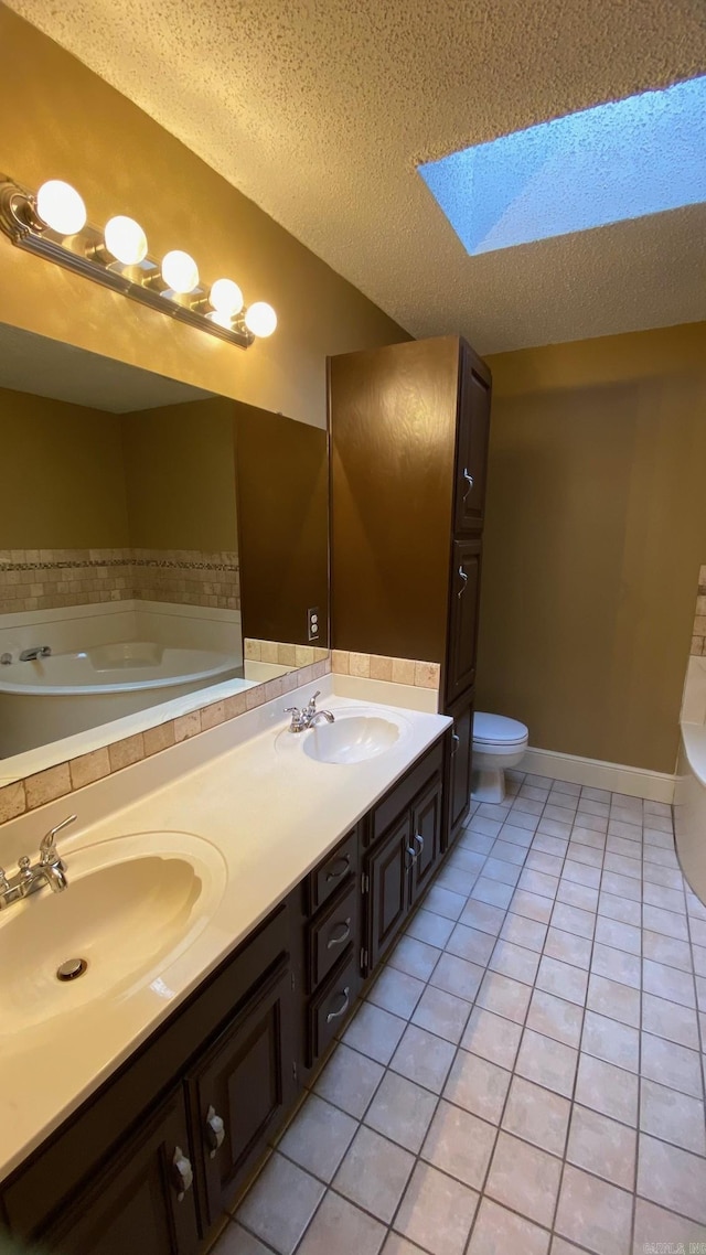 bathroom featuring a textured ceiling, a bathing tub, a skylight, tile patterned floors, and vanity