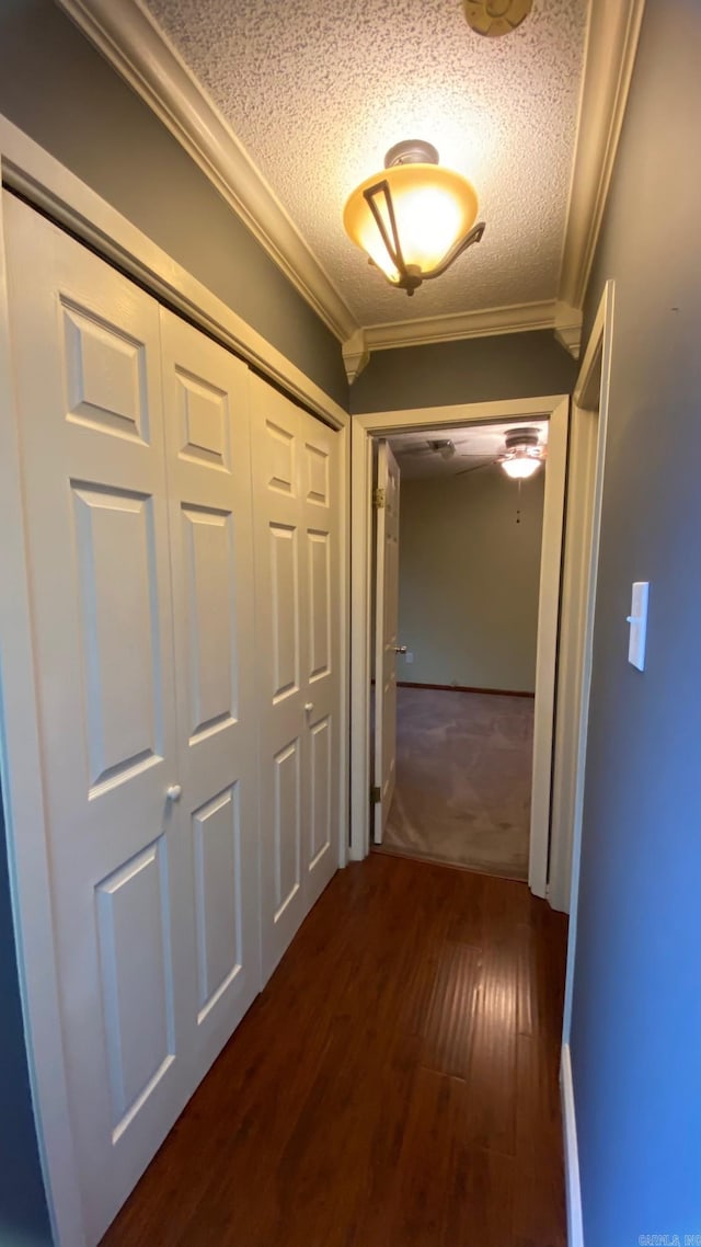 hallway with dark hardwood / wood-style flooring, a textured ceiling, and ornamental molding