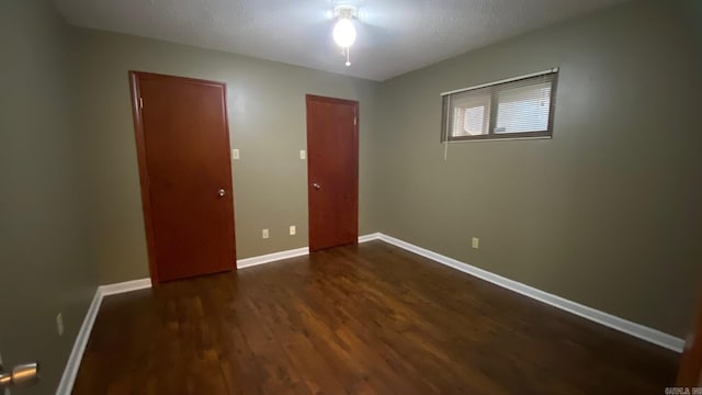 unfurnished bedroom featuring a textured ceiling and dark hardwood / wood-style floors