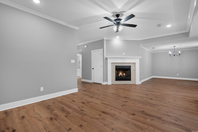 unfurnished living room with ceiling fan with notable chandelier, wood-type flooring, a tile fireplace, and ornamental molding