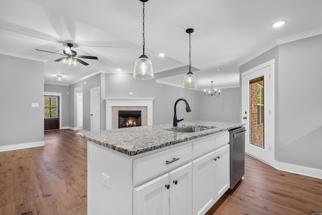 kitchen featuring sink, white cabinetry, hanging light fixtures, a kitchen island with sink, and light stone countertops