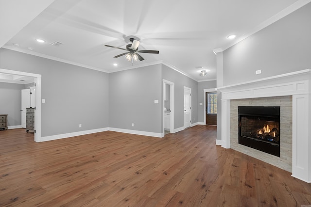 unfurnished living room with ceiling fan, crown molding, hardwood / wood-style flooring, and a tile fireplace