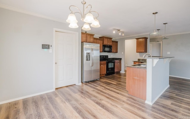 kitchen with a notable chandelier, black appliances, sink, hanging light fixtures, and a kitchen breakfast bar