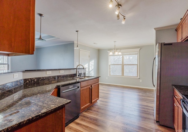 kitchen with stainless steel appliances, dark stone counters, ornamental molding, pendant lighting, and sink