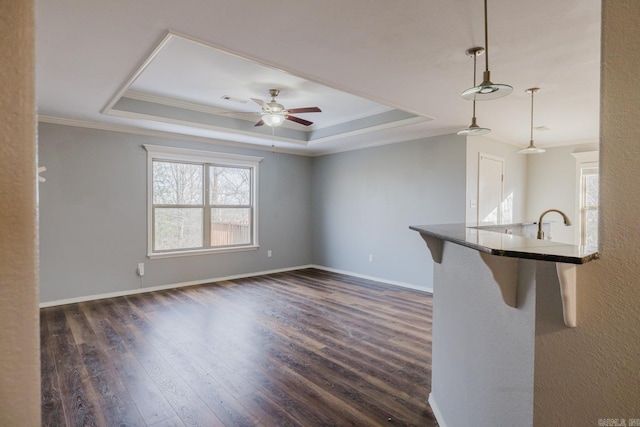 unfurnished living room featuring dark wood-type flooring, ornamental molding, a raised ceiling, and ceiling fan