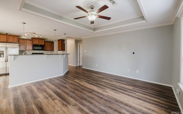 kitchen featuring decorative light fixtures, a center island with sink, stainless steel refrigerator with ice dispenser, a tray ceiling, and ornamental molding