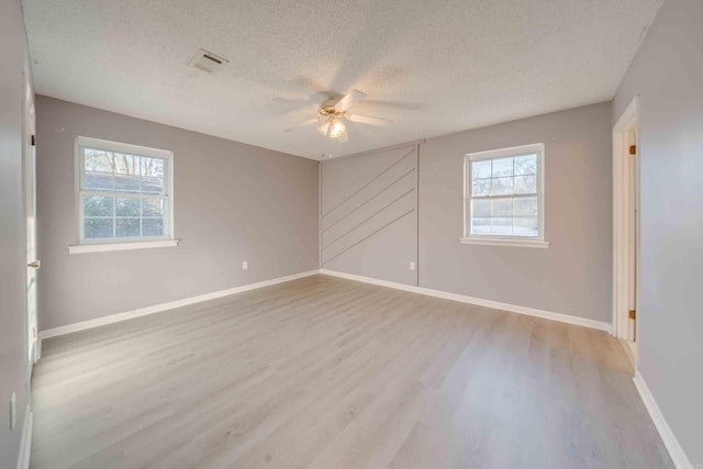 spare room with a textured ceiling, ceiling fan, plenty of natural light, and light hardwood / wood-style flooring