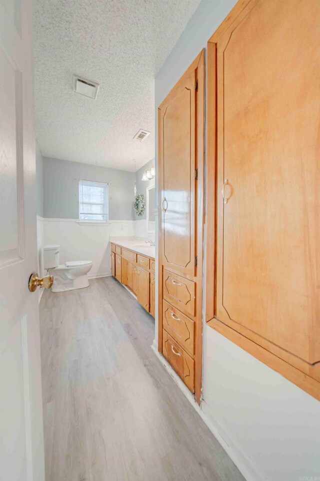 bathroom featuring hardwood / wood-style flooring, a textured ceiling, toilet, and vanity