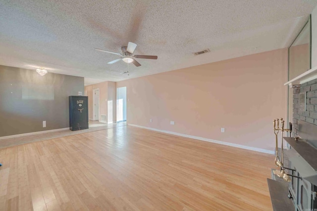 unfurnished living room with a textured ceiling, ceiling fan, and light hardwood / wood-style flooring