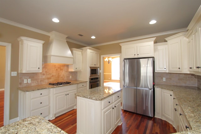 kitchen with light stone countertops, stainless steel appliances, white cabinetry, and custom range hood