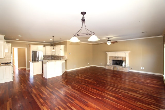 interior space with decorative light fixtures, a fireplace, decorative backsplash, crown molding, and appliances with stainless steel finishes