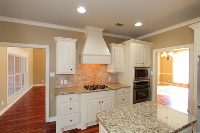 kitchen featuring light stone counters, white cabinets, stainless steel appliances, and custom range hood